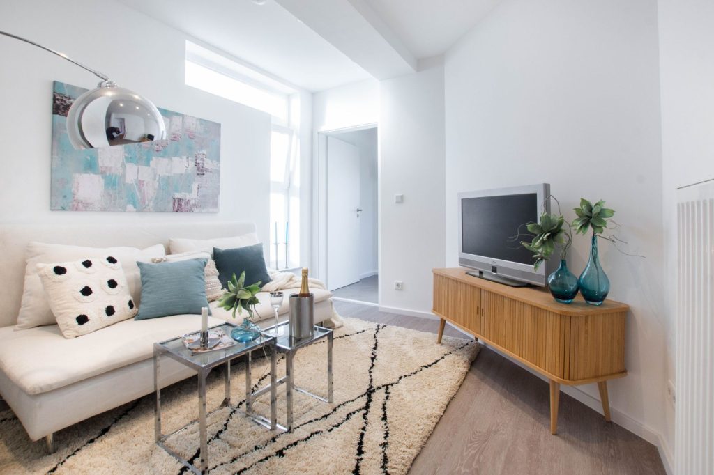 Heike Uhlemann – Deine Home Staging Expertin. Auf dem Foto ist eine weiße Couch vor einer weißen Wand zu sehen. Dadurch nimmt die Couch optisch weniger Platz im Raum ein.